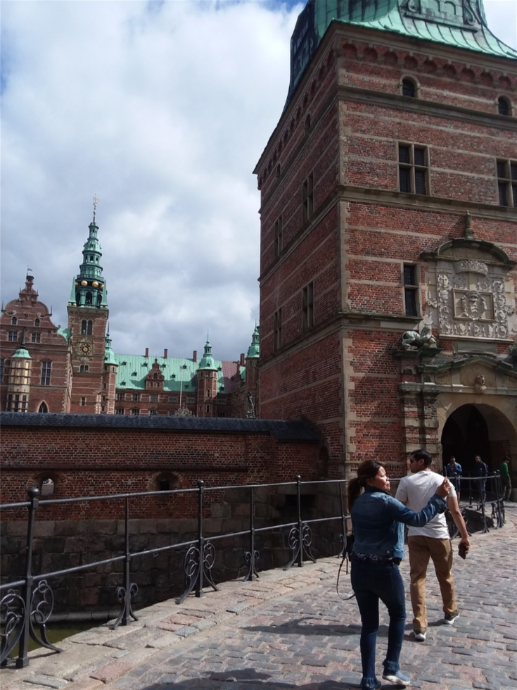 And here is one view of the entrance to Frederiksborg Slot. Farida can be seen in front of me taking photos as we all are doing. And Rayhend is in front of her. The bell tower of this castle is on what is called the Chapel Wing. There are 3 wings of this castle. Sculptures on some of the gables above some windows are of famous historical persons like Alexander the Great, Julius Caesar, and 1 or 2 from Danish history. I do not know who is depicted though. I did recognize Neptune  or Poseidon and several other of the Roman or Greek gods in a long row of sculptures in the Terrace Wing.