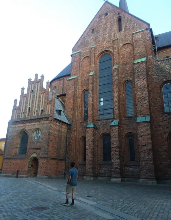 We are about to pass the north side of Roskilde Cathedral at Oluf Mortensens' porch built around 1450. The gable was constructed in the Late Medieval Gothic architectural style of North Germany.