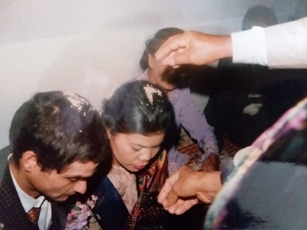 They already dropped stuff onto my head and now they are dropping some stuff onto the head of my new wife. This ritual was one of many rituals at the wedding reception after we got married. The wedding festivities lasted for two days.