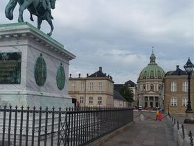 A second view from the center of Amalienborg Palace courtyard with the equistrian statue with King Fredrik V in the forground and Fredricks'Church in the background.